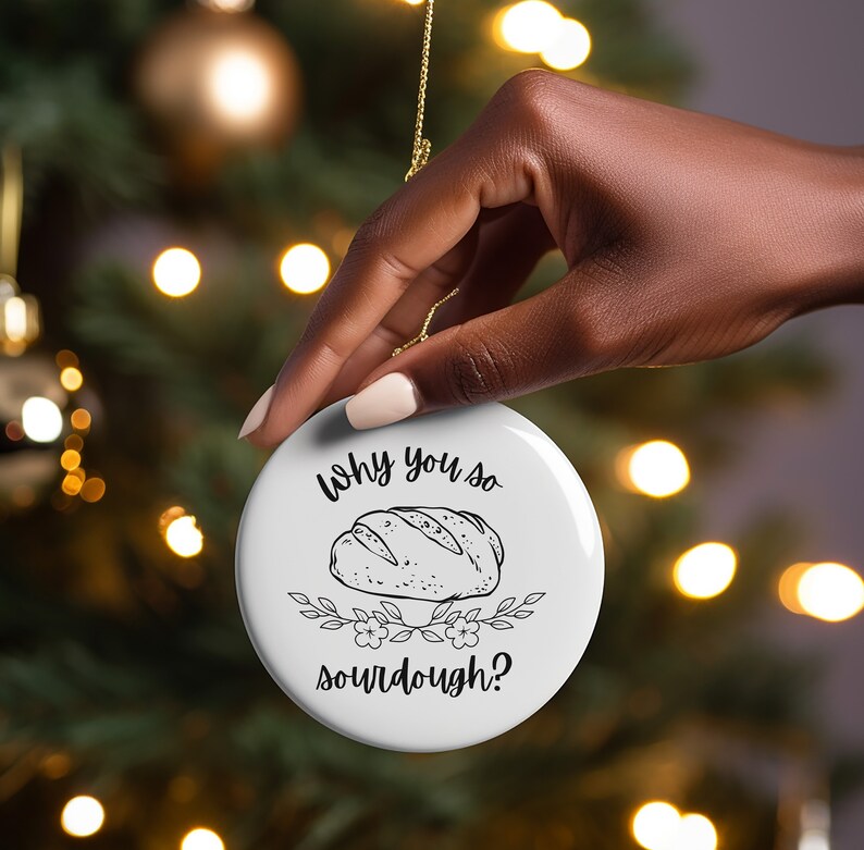 Peut inclure: Ornement de No&euml;l rond blanc avec du texte noir qui dit "Why you so sourdough?" et une illustration en noir et blanc d'une miche de pain au levain.