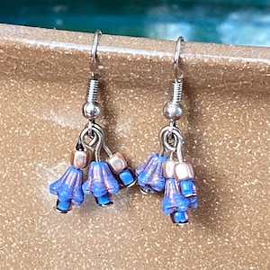 May include: A pair of silver dangle earrings with blue and copper colored glass beads shaped like bells.