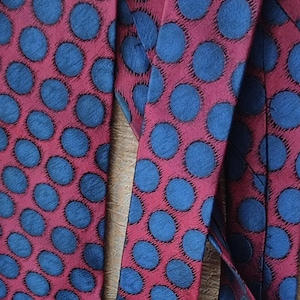 May include: Two red ties with a blue polka dot pattern. The ties are made of a silky material.