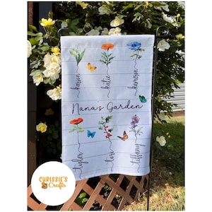 May include: A white garden flag with a floral design and the text "Nana's Garden". The flag has the names "Karson", "Katie", "Cameron", "Tyler", "Tori", and "Tiffany" written on it.