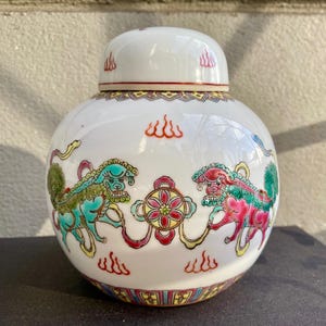 May include: White porcelain jar with a lid, decorated with colorful mythical creatures and floral designs. The jar has a traditional Chinese style.