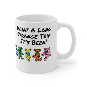 May include: White ceramic coffee mug with a black graphic that says "What a long strange trip it's been!" and five colorful dancing bears.