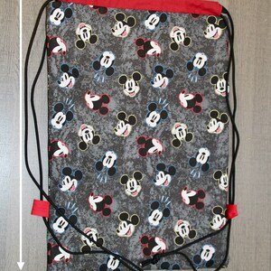 Puede incluir: Una bolsa de cord&oacute;n negro con la parte superior roja y un estampado de Mickey Mouse. La bolsa mide 43 cm de alto y 30 cm de ancho.