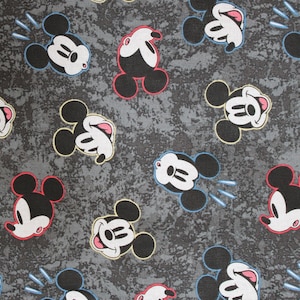 Puede incluir: Una tela gris con un patr&oacute;n repetido de cabezas de Mickey Mouse en blanco y negro. Las cabezas de Mickey Mouse sonr&iacute;en y tienen la lengua fuera. Algunas de las cabezas de Mickey Mouse tienen acentos rojos, amarillos o azules.