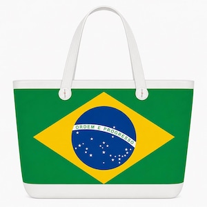 May include: A white-handled tote bag featuring the Brazilian flag. The bag's design includes a green background, a yellow diamond, and a blue circle with stars and text. The bag has a white base and handles.