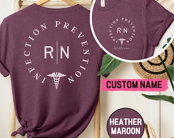 May include: A heather maroon t-shirt with a white circle design that says "Infection Prevention" with a caduceus symbol and the letters "RN" in the center. The text "William" is on the front of the shirt.
