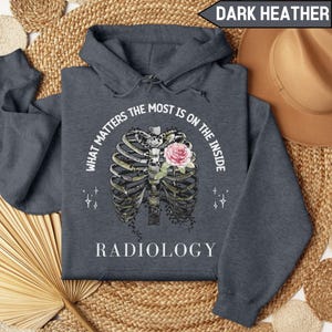 May include: Dark heather grey hoodie with a white graphic of a ribcage with a rose inside. The text "What matters the most is on the inside" is above the graphic and the word "Radiology" is below the graphic.