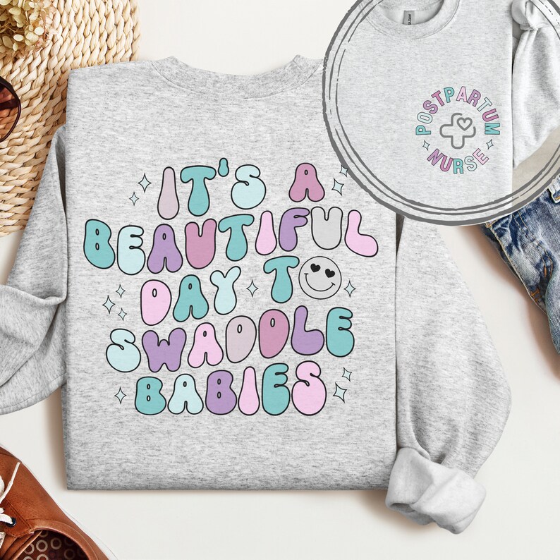 May include: A gray sweatshirt with the text "It's a beautiful day to swaddle babies" in colorful, bubble-like letters. The text is surrounded by small white stars.