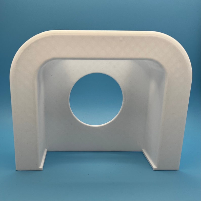 May include: White plastic cover with a round opening in the center. The cover is designed to fit over a circular object.