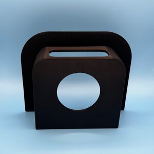 May include: Black plastic phone stand with a circular cutout for a phone or other device.
