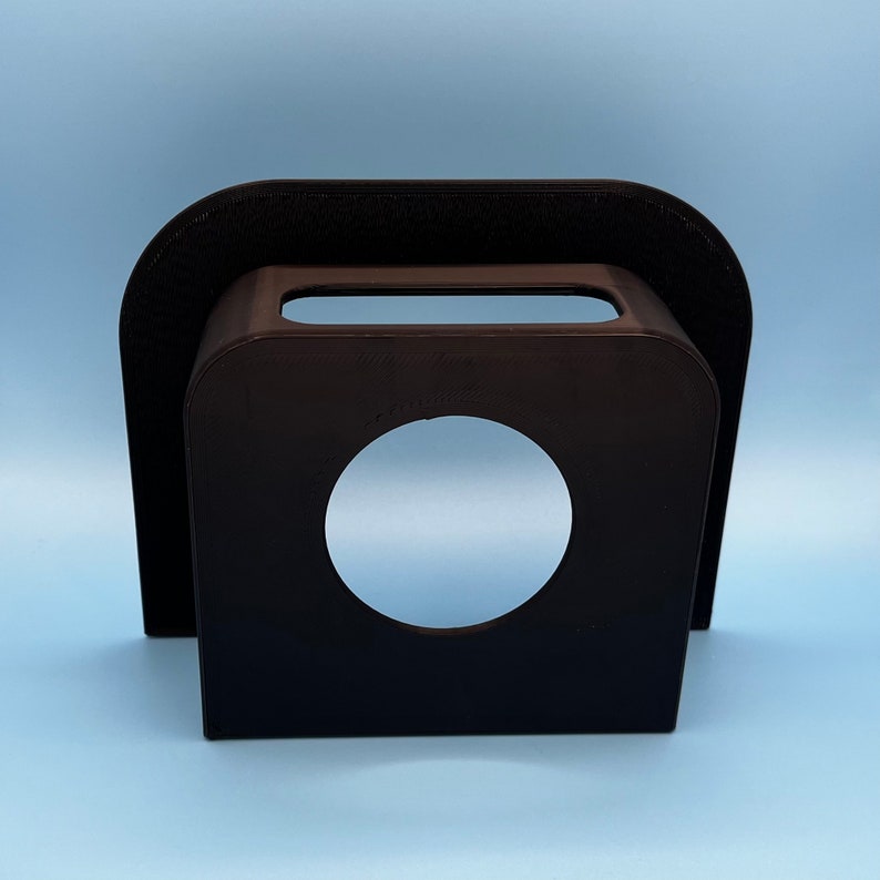 May include: Black plastic phone stand with a circular cutout for a phone or other device.