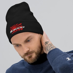 May include: Black beanie with the text "S2000 JDM" in white and red. The design includes a rising sun graphic. The beanie is made of a soft material and is suitable for cold weather.