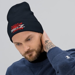 May include: Navy blue beanie with a red and white graphic of a rising sun and the text "350Z JDM". The beanie is made of a soft material and is designed to be worn on the head. This hat is a stylish accessory.