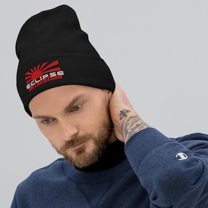 May include: Black beanie featuring a red and white graphic of a rising sun with the text "ECLIPSE Mitsubishi". The beanie is made of a soft material and is suitable for cold weather.