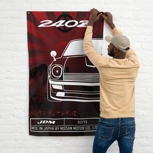 Peut inclure: Une affiche rouge et blanche avec une illustration en noir et blanc d'une voiture Nissan 240Z. L'affiche contient le texte "240Z", "Nissan Fairlady Z", "JDM", "02/73", et "MFD. IN JAPAN BY NISSAN MOTOR CO., LTD".