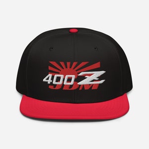 Puede incluir: Gorra de béisbol negra y roja con un logotipo bordado en blanco que dice "400Z JDM" y un gráfico de sol naciente rojo.