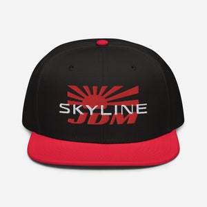 Puede incluir: Gorra de béisbol negra y roja con un sol naciente rojo y las palabras "SKYLINE JDM" bordadas en la parte delantera.