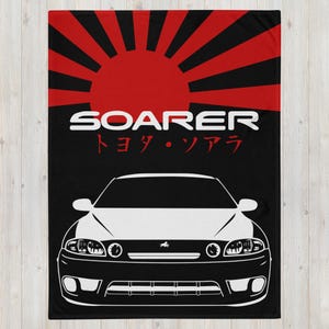 May include: A black and white illustration of a Toyota Soarer car with the text "SOARER" and "トヨタ・ソアラ" in red on a black background with a red and white rising sun graphic.