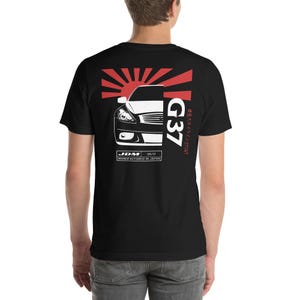 May include: Black t-shirt with a white graphic of a car, a rising sun, and the text "G37" and "JDM 08/17 MANUFACTURED IN JAPAN".