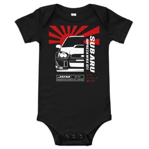 Puede incluir: Body de bebé negro con un gráfico blanco de un coche Subaru Impreza WRX STI y detalles en rojo. El diseño incluye el texto "SUBARU Impreza WRX STI" y "JDM 05/04 Fabricado en Japón".