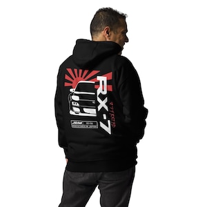 May include: Black hooded sweatshirt with a white graphic of a red rising sun, a car, and the text "RX-7" and "JDM 92/95 MANUFACTURED IN JAPAN".