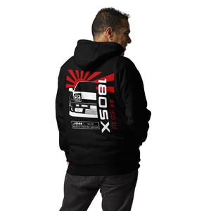 Könnte beinhalten: Schwarzer Hoodie mit einem roten und weißen japanischen Sonnenaufgang-Motiv und einer weißen Silhouette eines 180SX-Autos. Der Text "180SX" ist in Weiß mit rotem Umriss und der Text "S13 87-91 180SX" ist in Weiß. Der Text "JDM 84-91 MANUFACTURED IN JAPAN" ist in Weiß.
