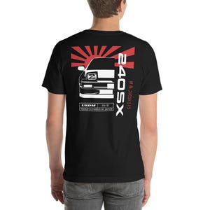 Puede incluir: Camiseta negra con un gráfico blanco de un coche, un sol naciente y el texto "240SX" y "USDM 05/92 MANUFACTURED IN JAPAN".