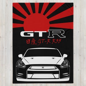 May include: A black and white illustration of a Nissan Skyline GT-R R35 with a red rising sun behind it. The text "GTR" and "日産 GT-R R35" is printed below the car.