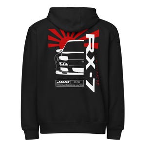 May include: Black hooded sweatshirt featuring a white and red graphic of a car with the text "RX-7" and "JDM Manufactured in Japan." The design includes a rising sun graphic. The sweatshirt has a drawstring hood.