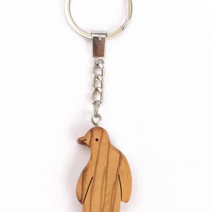 Llavero de madera de olivo con diseño de pingüino.
