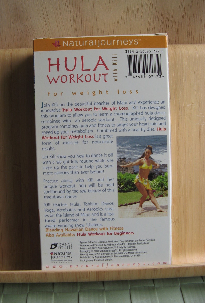 Peut inclure: Un bo&icirc;tier de DVD bleu et blanc avec une photo d'une femme en haut jaune et jupe florale dansant sur une plage. Le bo&icirc;tier est pour un Hula Workout for Weight Loss avec Kili. Le texte sur le bo&icirc;tier indique "Naturaljourneys" et "Hula Workout for Weight Loss".