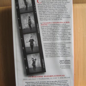 Peut inclure: Une cassette VHS en noir et blanc mettant en sc&egrave;ne une danseuse orientale. La cassette est intitul&eacute;e "Cassandra : Introduction &agrave; la danse du ventre". La couverture comprend une s&eacute;rie de photos en noir et blanc de la danseuse dans diff&eacute;rentes poses. Le texte sur la couverture indique "Approx. 60 min. 12 min. performance 48 min. instruction. All Rights Reserved &copy; 1998 TURQUOISE INTERNATIONAL."