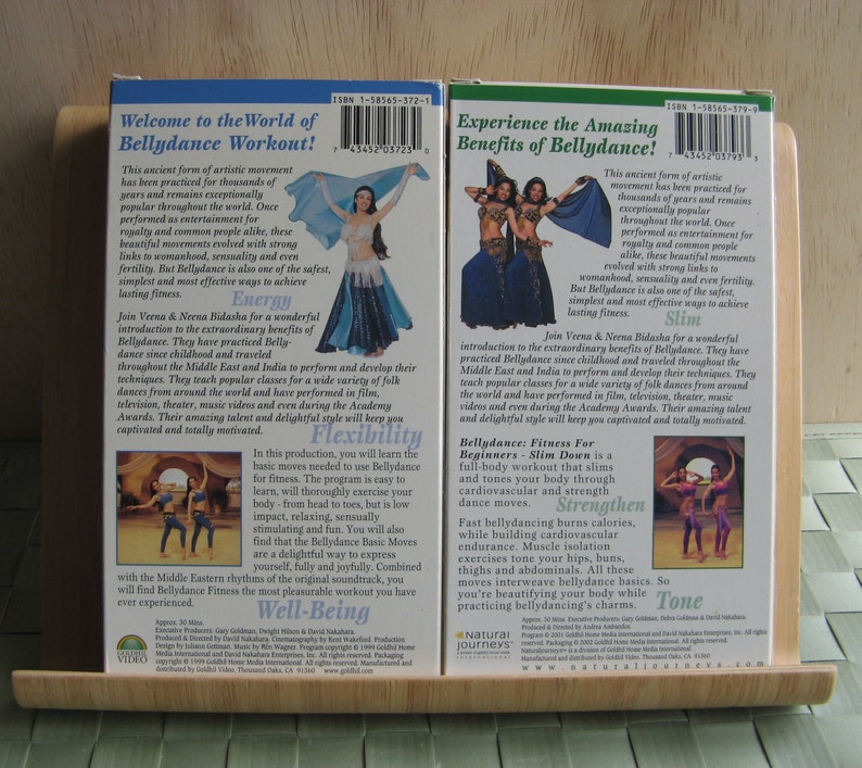 Peut inclure: Deux cassettes VHS avec des pochettes color&eacute;es repr&eacute;sentant des femmes en tenue de danse du ventre traditionnelle. La cassette de gauche est intitul&eacute;e "Bienvenue dans le monde du Bellydance Workout !" et la cassette de droite est intitul&eacute;e "D&eacute;couvrez les incroyables bienfaits de la danse du ventre !". Les deux cassettes comportent le texte "Natural Journeys" et une adresse de site web.