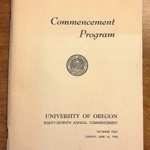 May include: A tan paper program for the University of Oregon's 87th annual commencement ceremony. The program features the university's seal and the date Sunday, June 14, 1964.