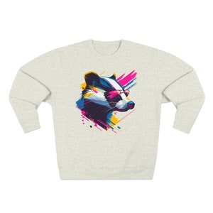 May include: A grey sweatshirt with a colorful graphic of a badger wearing sunglasses. The badger is in a stylized, abstract design with splashes of pink, blue, and yellow.