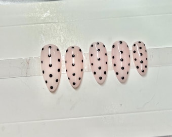 May include: Set of six pink and black polka dot false nails. The nails are almond shaped and have a glossy finish.