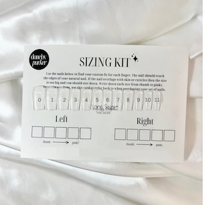 May include: A white sizing kit for press-on nails. The kit includes 11 clear plastic nail tips numbered 0-11. The kit also includes a chart with spaces to write down the size of each nail for each finger, labeled "left" and "right". The nail shape is labeled "Long Square".