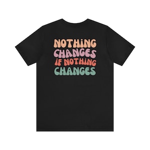Puede incluir: Camiseta negra con un estampado gráfico colorido que dice "NOTHING CHANGES IF NOTHING CHANGES".