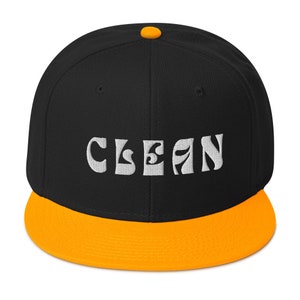 May include: Black and orange baseball cap with the word "CLEAN" embroidered in white on the front.