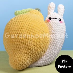 Pode incluir: Padrão de crochê para um brinquedo amigurumi em forma de caracol de limão. O caracol é branco com uma concha de limão amarela e uma folha verde. O padrão está disponível para download em PDF.