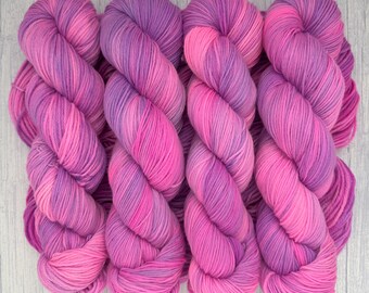 May include: Four skeins of yarn in shades of pink and purple. The yarn is twisted into a spiral shape.