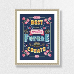 May include: Framed cross-stitch artwork with the quote "The best way to predict the future is to create it." The text is in various colors, including blue, pink, and yellow, with floral accents. The frame is gold.