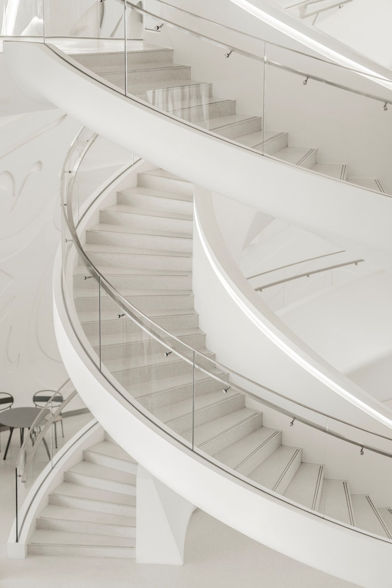 May include: A white spiral staircase with glass railings. The staircase is in a modern building with white walls.
