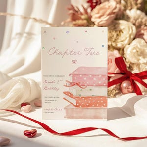 Puede incluir: Una tarjeta de invitación de cumpleaños con el texto "Chapter Two" y "Sarah's 2nd Birthday". La tarjeta presenta una ilustración de acuarela de libros apilados con lazos. La tarjeta está decorada con estrellas y un lazo, con una cinta roja y caramelos en forma de corazón.