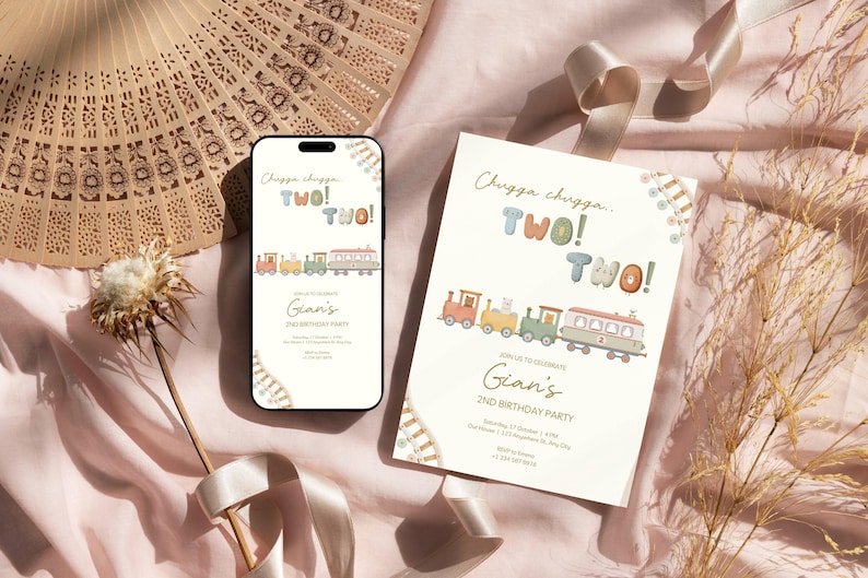 May include: A smartphone and a printed invitation with a train illustration and the text "Chugga chugga, TWO! TWO!" are displayed. The invitation is for Gian's 2nd birthday party. A decorative fan and ribbon are in the background.