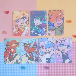 May include: Seven holographic trading cards featuring anime-style characters with vibrant colors. The cards showcase various characters with unique hairstyles, outfits, and expressions. The background is a mix of pastel colors and decorative elements.