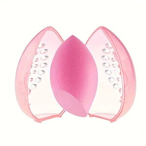 Könnte beinhalten: Rosaer Make-up-Schwamm mit einem rosa Plastik-Etui mit Netzdesign. Das Etui ist geöffnet und der Schwamm befindet sich darin.