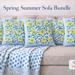 Op de afbeelding: Een bankarrangement met vijf vierkante kussenhoezen met een geel en blauw bloemmotief, en een bijpassende sprei. De kussens en de sprei hebben een witte achtergrond. De tekst "Spring Summer Sofa Bundle" staat bovenaan.