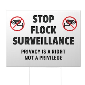 May include: A white yard sign with the text "STOP FLOCK SURVEILLANCE" and "PRIVACY IS A RIGHT NOT A PRIVILEGE" in black. The sign has two red circles with a crossed-out camera icon. It is mounted on a metal stake.