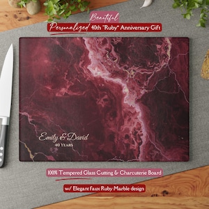 May include: A rectangular tempered glass cutting board with a faux ruby marble design. The board is personalized with the names "Emily & David" and "40 YEARS". Text at the top reads "Personalized 40th 'Ruby' Anniversary Gift".